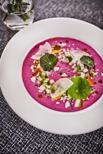 a white plate with a red soup with vegetables in it at Energihotellet in Nesflaten