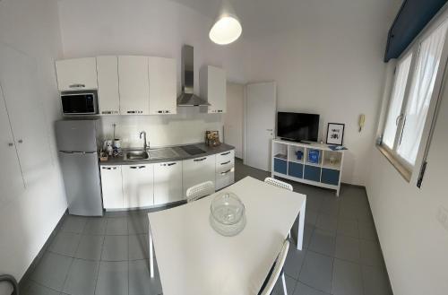 a white kitchen with a table and a refrigerator at La Casa del Nonno - Villapiana in Villapiana