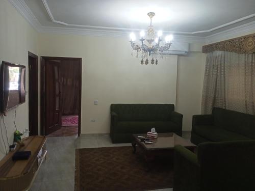 a living room with a green couch and a chandelier at 19 Abu Al-Hol Tourist Street, Al-Haram, Nazlet Al-Samman in Cairo
