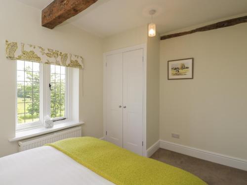 een slaapkamer met een bed en 2 ramen bij North Lodge in Malmesbury