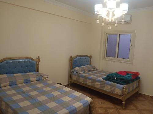 a bedroom with two beds and a chandelier at 19 Abu Al-Hol Tourist Street, Al-Haram, Nazlet Al-Samman in Cairo