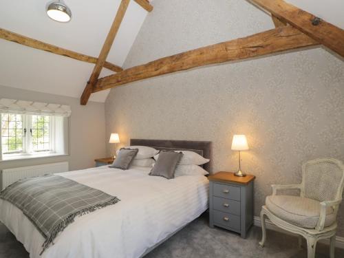 a bedroom with a large bed and a chair at The Cottage in Malmesbury