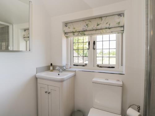 a white bathroom with a sink and a window at The Cottage in Malmesbury
