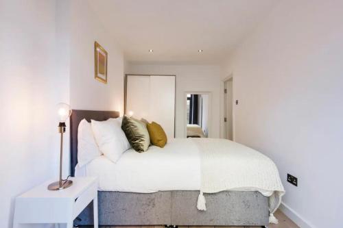 a bedroom with a bed with white sheets and gold pillows at Cozy 1 bedroom apartment in Notting Hill in London