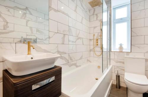 a bathroom with a sink and a tub and a toilet at Cozy 1 bedroom apartment in Notting Hill in London
