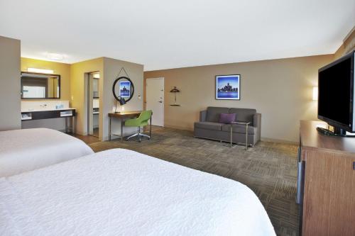 a hotel room with two beds and a flat screen tv at Hampton Inn Commerce/Novi in Walled Lake