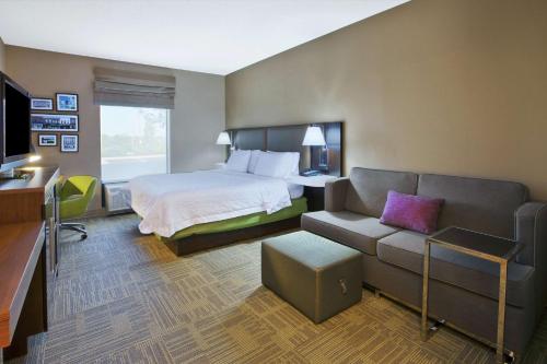 um quarto de hotel com uma cama e um sofá em Hampton Inn Commerce/Novi em Walled Lake