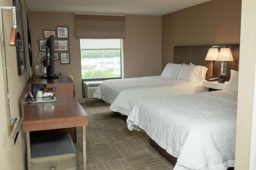 a hotel room with two beds and a desk and a window at Hampton Inn Commerce/Novi in Walled Lake