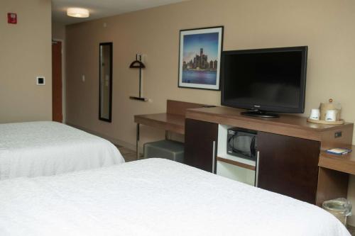 a hotel room with two beds and a flat screen tv at Hampton Inn Commerce/Novi in Walled Lake