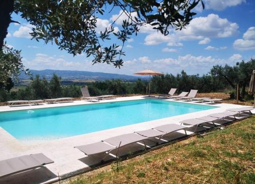 CapodacquaにあるAgriturismo Villa Val D'Oliviのラウンジチェアとパラソル付きのスイミングプールを併設しています。