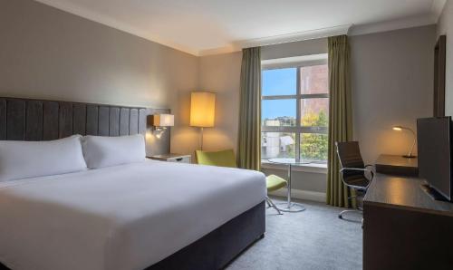 a hotel room with a bed and a desk and a window at Hilton Dublin in Dublin