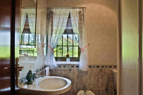 a bathroom with a sink and a window and a toilet at Casa Rural Las Huertas de Roque in Monachil