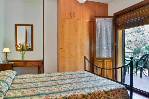 1 dormitorio con cama y vistas a un balcón en Casa Rural Las Huertas de Roque, en Monachil