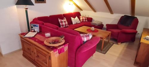 salon z czerwoną kanapą i stołem w obiekcie Haus Bergblick w mieście Mittenwald