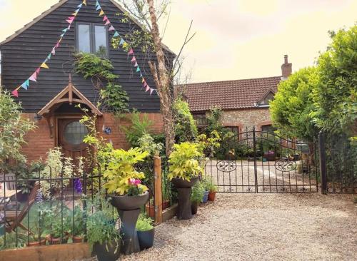 a house with a fence with potted plants in front of it at TAIL END: Bijoux Broads & Beach Base! Now with TV! in Stalham