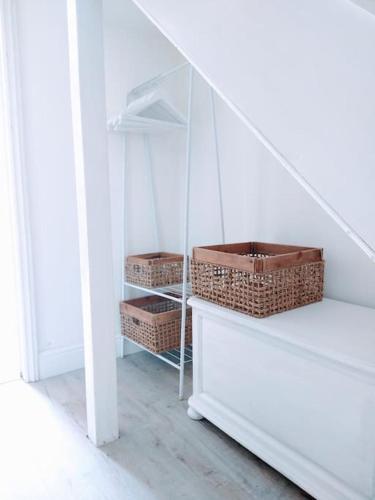a staircase with wicker baskets and a white shelf at TAIL END: Bijoux Broads & Beach Base! Now with TV! in Stalham