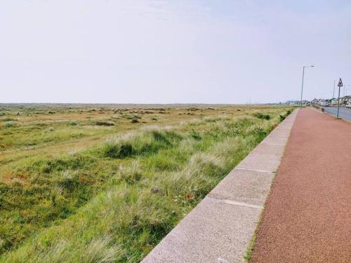 a path next to a field of grass next to a road at TAIL END: Bijoux Broads & Beach Base! Now with TV! in Stalham
