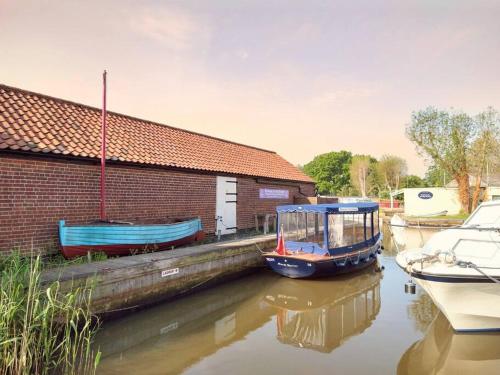 a small boat is docked next to a building at TAIL END: Bijoux Broads & Beach Base! Now with TV! in Stalham