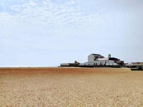 a sandy beach with a building in the background at TAIL END: Bijoux Broads & Beach Base! Now with TV! in Stalham