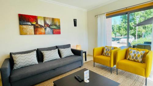 a living room with a couch and two yellow chairs at Branca by Check-in Portugal in Albufeira