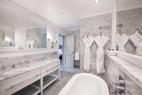 a bathroom with a tub and two sinks and a toilet at The Caledonian Edinburgh, Curio Collection by Hilton in Edinburgh