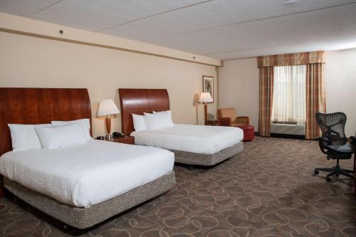 um quarto de hotel com duas camas e uma cadeira em Hilton Garden Inn Erie em Erie