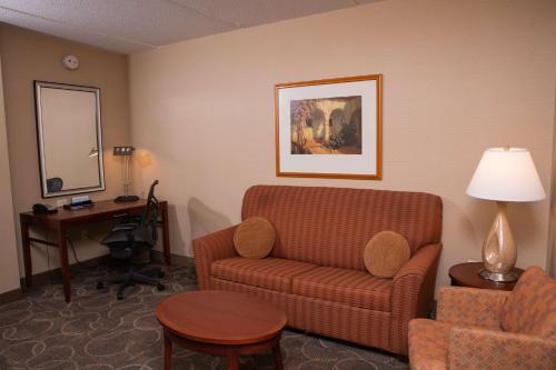 a hotel room with a couch and a desk and a chair at Hilton Garden Inn Erie in Erie