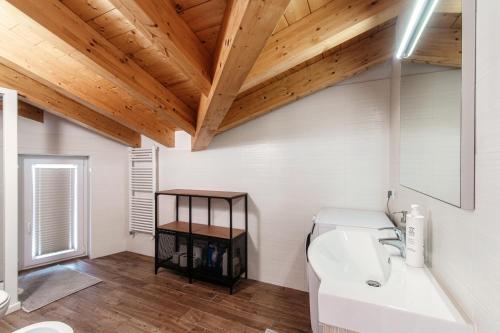 baño con lavabo blanco y techo de madera en Serendipity- by MyHomeInComo, en Lenno