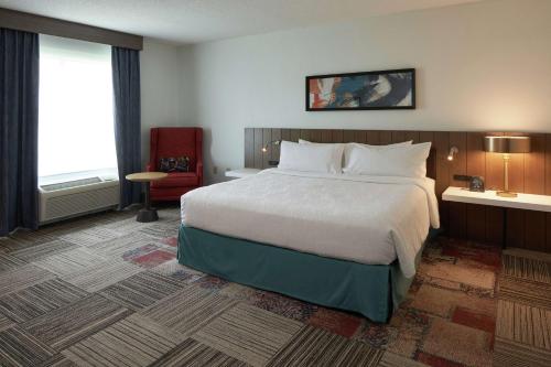 a hotel room with a large bed and a chair at Hilton Garden Inn Evansville in Evansville