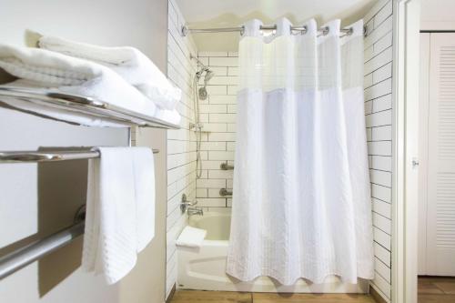 a white shower curtain in a bathroom with a tub at DoubleTree by Hilton Grand Key Resort in Key West
