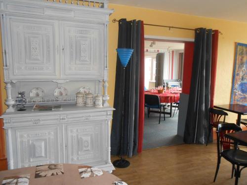 a living room with a large white cabinet and a dining room at Le Logis du Pré Braheux in Saint-Nabord