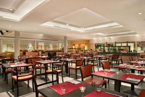 um restaurante com mesas e cadeiras com guardanapos vermelhos em Hilton Garden Inn Rome Airport em Fiumicino