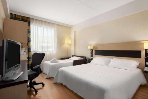 a hotel room with two beds and a flat screen tv at Hilton Garden Inn Rome Airport in Fiumicino