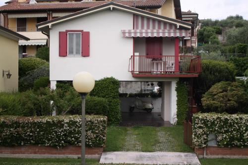 Casa bianca con finestra rossa e balcone. di Residenza Palmira Bardolino a Calmasino