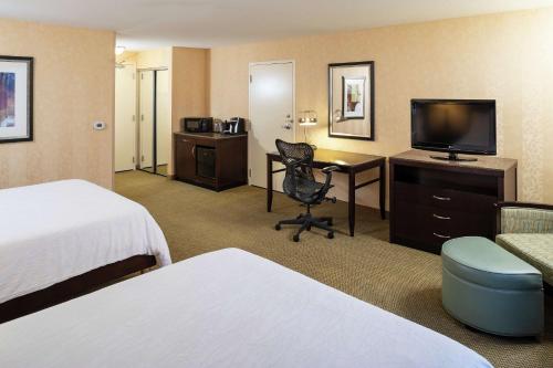 Habitación de hotel con cama y escritorio con TV. en Hilton Garden Inn Sioux Falls South en Sioux Falls