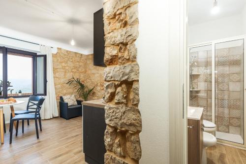 uma cozinha e sala de estar com uma parede de pedra em Dommu Anna em Baunei