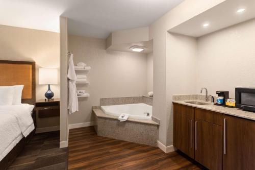 a bathroom with a tub and a bed and a sink at Hampton Inn by Hilton Fort Smith in Fort Smith