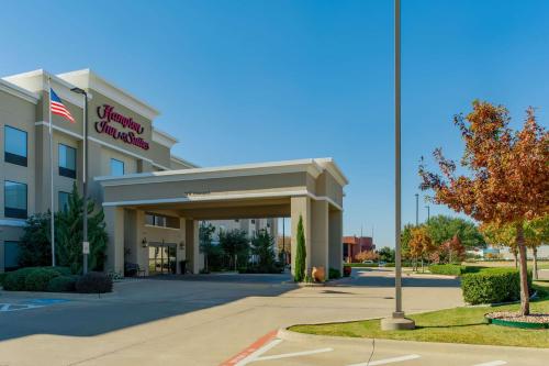 a hotel building with an american flag in front of it at Hampton Inn & Suites Fort Worth-Fossil Creek in Fort Worth