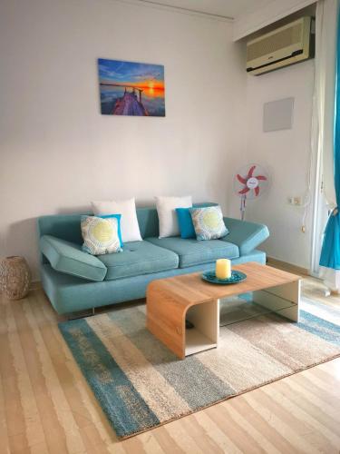a living room with a blue couch and a coffee table at Athena Apartment in Néa Péramos