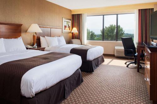 a hotel room with two beds and a desk at DoubleTree by Hilton Grand Junction in Grand Junction