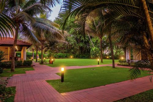 a courtyard with palm trees and a pathway with lights at DoubleTree by Hilton Hotel Goa - Arpora - Baga in Baga