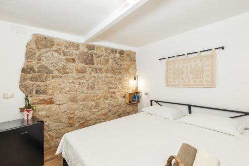 a bedroom with a stone wall and a bed at Dommu Anna in Baunei