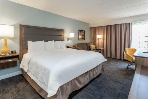 a hotel room with a large bed and a desk at Hampton Inn Groton/Mystic in Groton