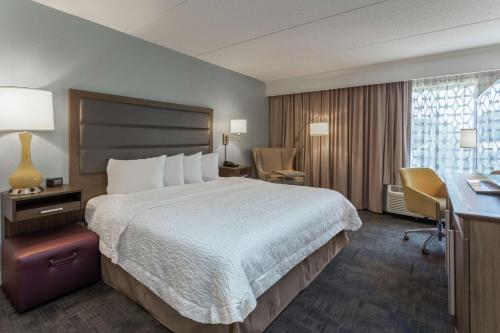 a hotel room with a large bed and a desk at Hampton Inn Groton/Mystic in Groton