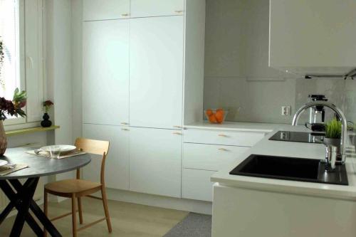 a kitchen with white cabinets and a sink and a table at Studio Kuopion kattojen yllä in Kuopio