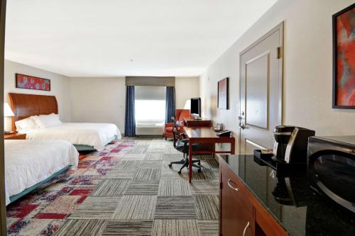 a hotel room with two beds and a desk and a television at Hilton Garden Inn Gulfport - Biloxi Airport in Gulfport