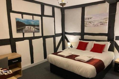 a bedroom with a large bed with red pillows at The Bugle Hotel in Titchfield