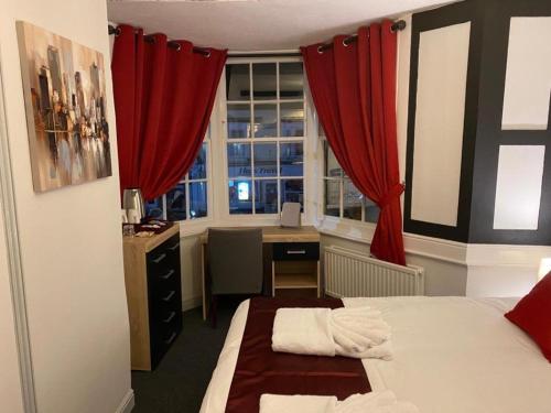 a bedroom with a bed and a desk and a window at The Bugle Hotel in Titchfield