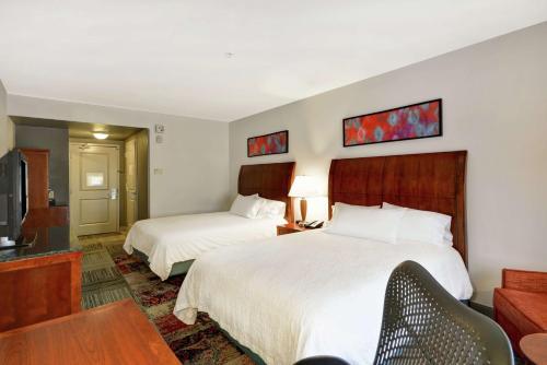 a hotel room with two beds and a television at Hilton Garden Inn Gulfport - Biloxi Airport in Gulfport