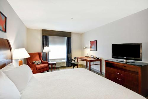a hotel room with a bed and a flat screen tv at Hilton Garden Inn Gulfport - Biloxi Airport in Gulfport